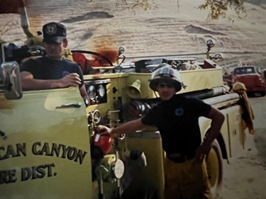 Two firefighters standing beside an American Canyon Fire District fire engine outdoors.