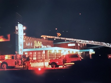 Firefighters and fire engines responding to a nighttime building fire.